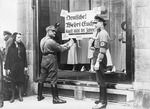 Unbekannter Fotograf - SA- und SS-Mann bekleben das Schaufenster mit Boykott-Plakaten: Deutsche! Wehrt Euch! Kauft nicht bei Juden!
